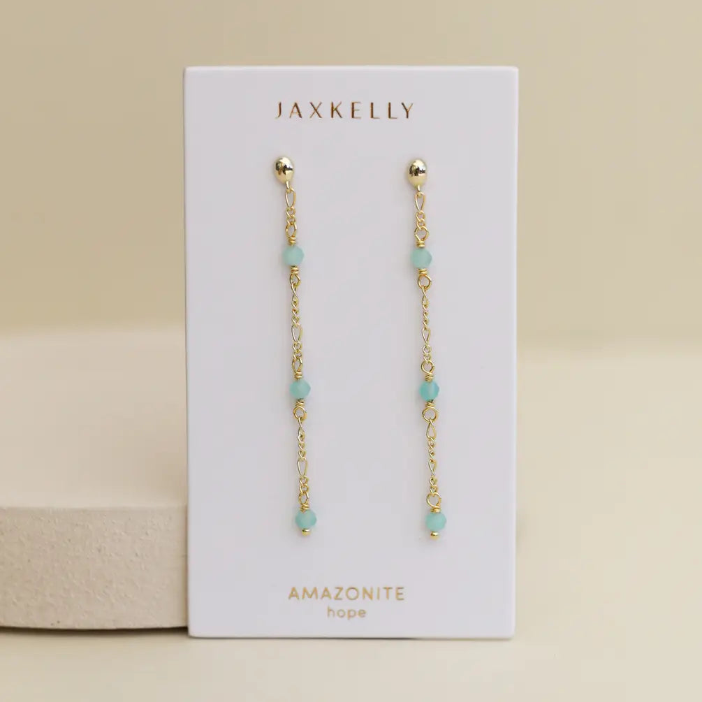 A pair of JaxKelly Gemstone Chain Drop earrings featuring small Amazonite beads and 18k gold plating, displayed on a white card labeled "JaxKelly" and "Amazonite hope" against a neutral background.
