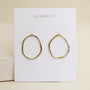 The Gold Organic Hoop by JaxKelly features 18k gold plating and sterling silver posts, shown on a white card with the brand name in gold letters against a soft beige background.