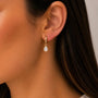 A person wearing a Teardrop Charm Hoop - White CZ by JaxKelly.