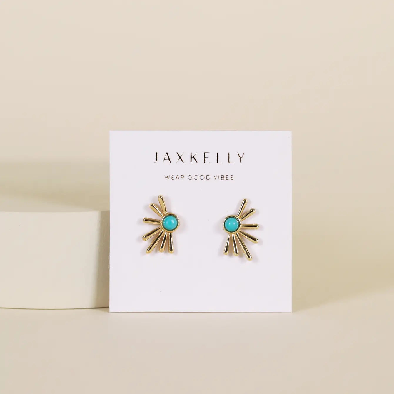 The Sun Ray - Turquoise earrings are gold-plated studs with vibrant turquoise stones, displayed on a white JaxKelly Wear Good Vibes card against a neutral beige background.
