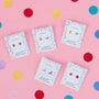 The Lemon Enamel Flat Back Kids Earrings, perfect for sensitive ears, are shown on display cards over a pink confetti background alongside colorful fruit-themed designs like cherries, oranges, and strawberries. Hypoallergenic and stylish for kids.