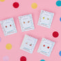Five pairs of Strawberry Enamel Flat Back Kids Earrings are displayed on decorative cards against a pink background with scattered red, yellow, and blue confetti circles—perfect for sensitive ears.