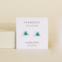 A pair of small, triangle-shaped Turquoise - Mini Energy Gems - Grounding studs by JaxKelly with sterling silver posts are displayed on a white card labeled "Wear Good Vibes" against a neutral background.