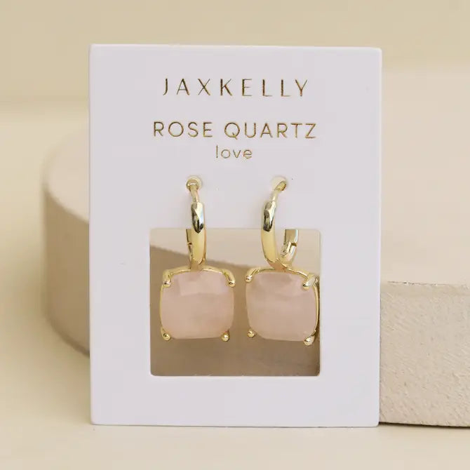 JaxKelly Gemstone Mini Drop - Rose Quartz earrings feature gold plated hoops with square rose quartz stones on an off-white ROSE QUARTZ love card. These tarnish-free earrings are displayed against a soft beige background.