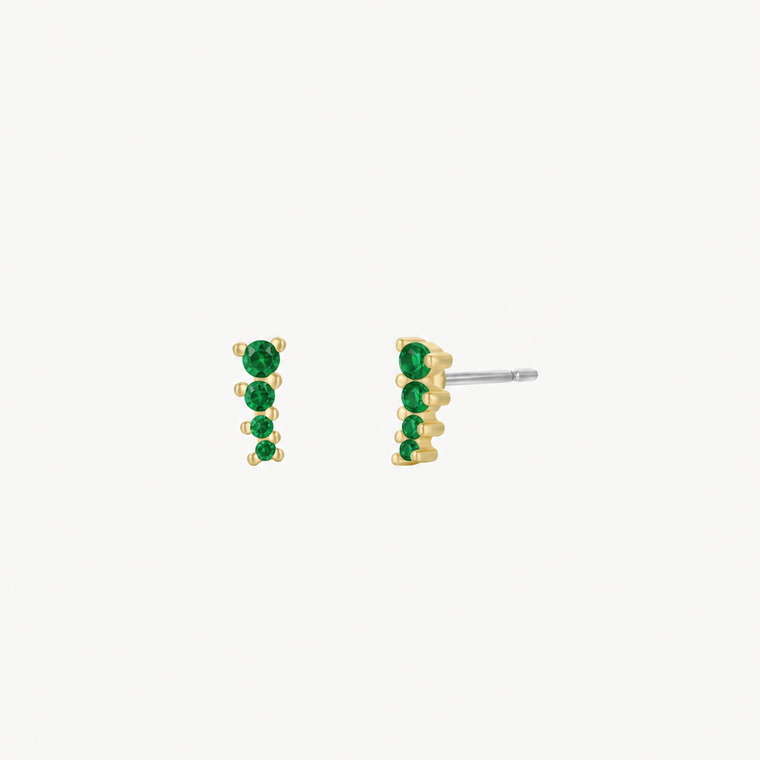 The JaxKelly Mini Crawler - Emerald CZ - Gold Earrings are 18K gold plated stud earrings featuring a vertical row of four small round emerald cubic zirconia stones. Hypoallergenic for sensitive ears and shown on a plain white background.