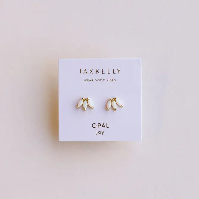 A pair of small gold-plated White Opal Crown Stud earrings by JaxKelly, displayed on a white card with "Wear Good Vibes" and "Opal Joy" printed on it.