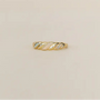 Gold ring with a twisted design on a beige background