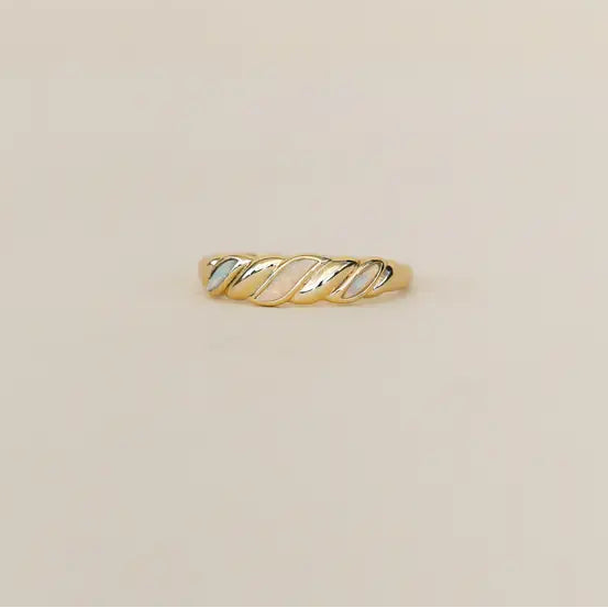 Gold ring with a twisted design on a beige background