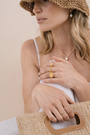 Woman in a woven sun hat and white dress wearing gold jewelry, including the Gold Signet Ring, a necklace, and pearl earrings, holding a straw handbag with leather handle—perfect for everyday wear.