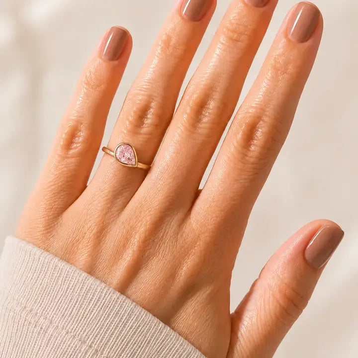 JaxKelly Halo Drop Gold Ring - Pink CZ, a tarnish-free gold ring featuring a teardrop-shaped pink crystal worn on a hand.