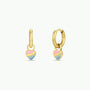 The Heart Enamel Charm Hoop features small gold hoops with dangling heart-shaped charms in pink, blue, and yellow enamel accents—hypoallergenic earrings for sensitive ears, shown on a plain white background.