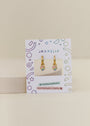 The Heart Enamel Charm Hoop earrings are gold hoops with rainbow heart charms for sensitive ears, shown on a white JaxKelly card with colorful geometric and celestial designs. The hypoallergenic pair is also kid-friendly.