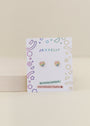 The Heart Enamel Flat Back Kids Earrings are small, heart-shaped studs in pastel colors with hypoallergenic, kid-friendly posts—perfect for sensitive ears and featuring colorful geometric designs on a white JaxKelly card.