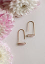 Two Rose Quartz Gemstone Drop - Love earrings by JaxKelly with minimalist gold plating and rectangular pink stones are displayed on a light surface among soft pink and white flowers, adding an elegant touch of gemstone jewelry.