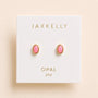 JaxKelly Oval Bezel - Pink Opal stud earrings in an oval shape with a gold bezel, displayed on branded packaging.