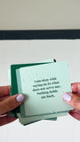 JaxKelly's Abundance Shower Affirmations, slightly wet, being displayed and shuffled through by a pair of hands.