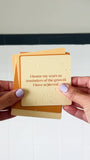 JaxKelly's Strength Shower Affirmations, slightly wet, being displayed and shuffled through by a pair of hands.