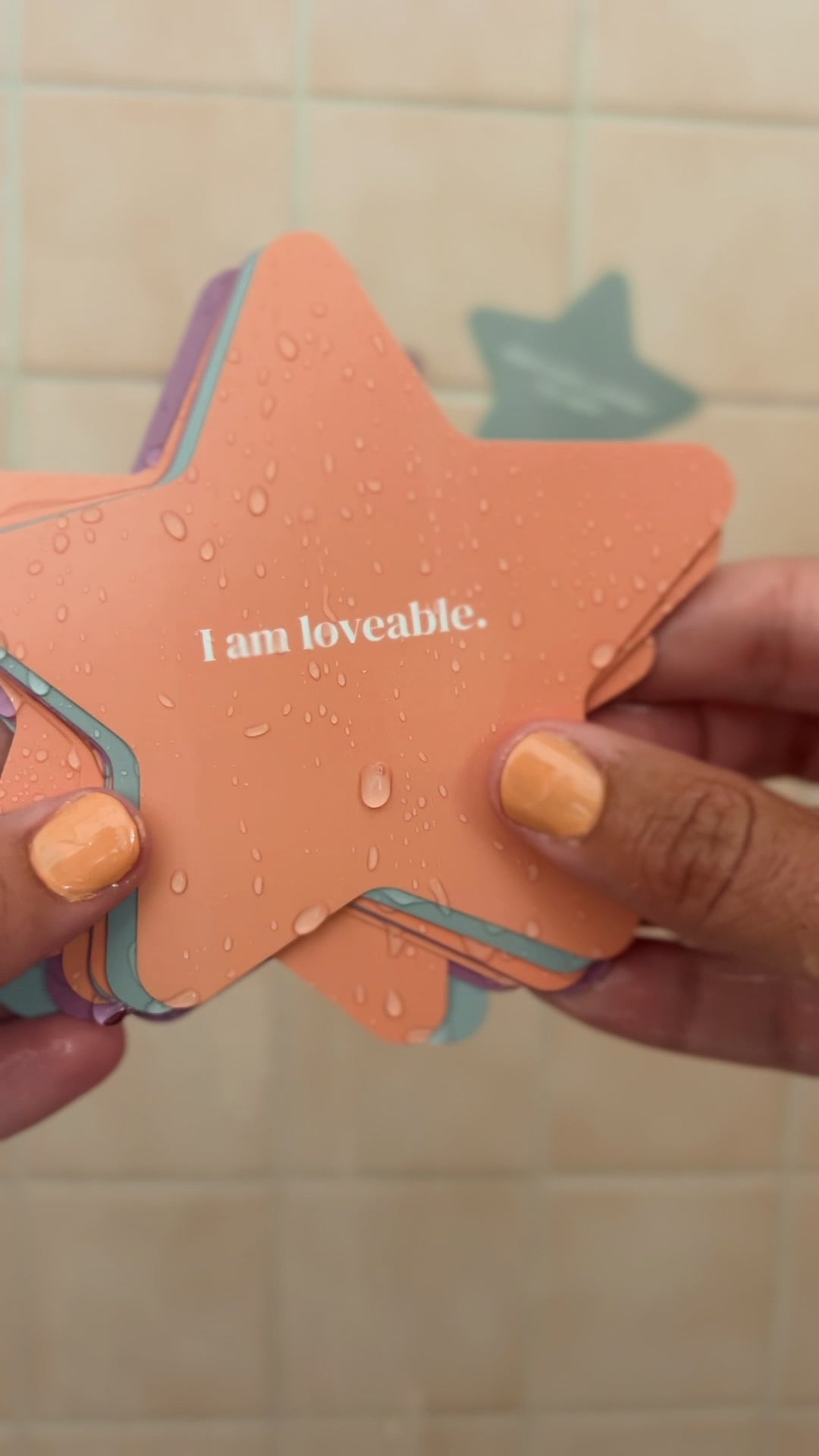 JaxKelly's Kids Shower Affirmations under running water, being placed on a white tiled shower wall.