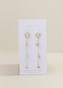 The Raw Gemstone Chain Drop Earring - Peach Moonstone features gold chain drop hoops with dangling chains and peach moonstone chips, displayed on a white JaxKelly card labeled "Peach Moonstone – new beginnings." Tarnish free for effortless elegance.
