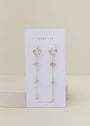 The Raw Gemstone Chain Drop Earring - Rose Quartz features gold chain drop hoops displayed on a white JaxKelly card labeled "Rose Quartz love," against a light beige background. These tarnish-free earrings add elegance to any look.