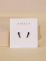 The Mini Crawler - Sapphire CZ - Gold Earrings by JaxKelly feature gold-plated studs with blue stones in a zigzag design. Displayed on a white JaxKelly card, these hypoallergenic earrings are perfect for sensitive ears.