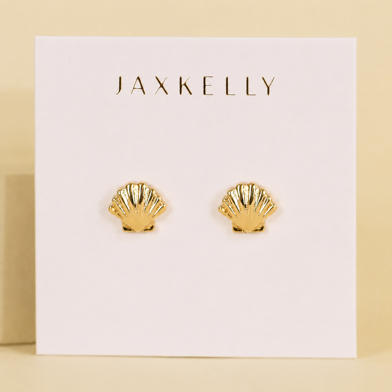 JaxKelly's Seashell Stud Earrings are hypoallergenic, tarnish-free, and perfect for daily wear. Displayed on a light beige card with the JaxKelly logo in gold, these elegant studs add a touch of shine to any look.