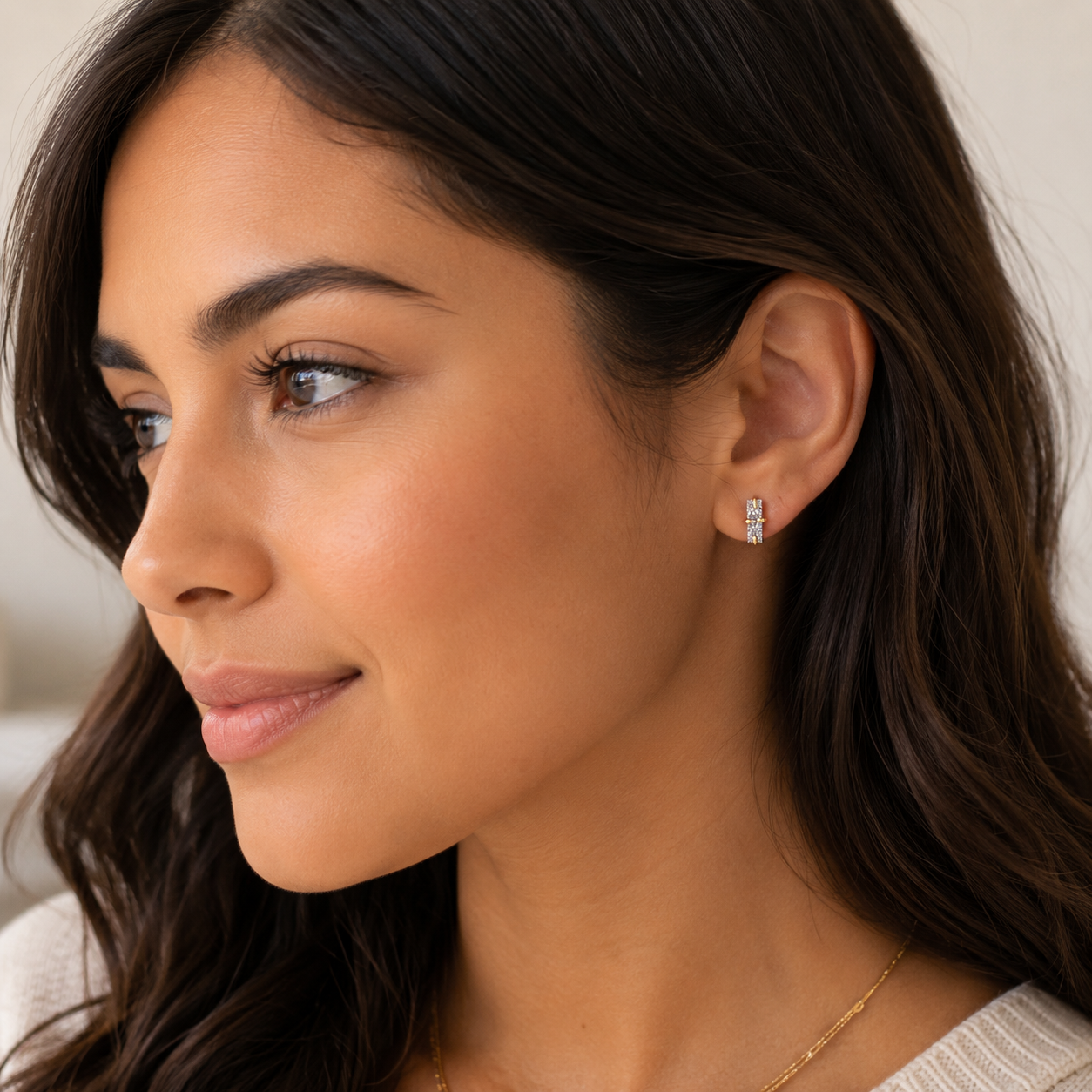 A woman with long brown hair and radiant skin wears JaxKelly's Silver Bar Druzy earrings and a delicate gold necklace. She looks to the side with a gentle smile, dressed in a light-colored top.