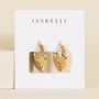 The JaxKelly Triple Arch Hoop Earrings feature a layered, twisted sculptural design in 18K gold, shown on a white branded card against a neutral background.