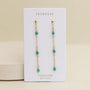 The JaxKelly Gemstone Chain Drop - Turquoise earrings, featuring small turquoise beads and 18k gold plating, are displayed on a white card labeled JaxKelly and Turquoise against a neutral background.