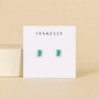 JaxKelly's Turquoise Baguette earrings, featuring small turquoise stones with gold prongs on a white card, are hypoallergenic—offering both style and comfort against a chic beige background.
