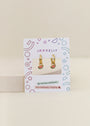 The Watermelon Enamel Charm Hoop earrings, ideal for sensitive ears, are shown on a JaxKelly card with colorful geometric patterns and labels stating Hypoallergenic and Kid-Friendly Posts.