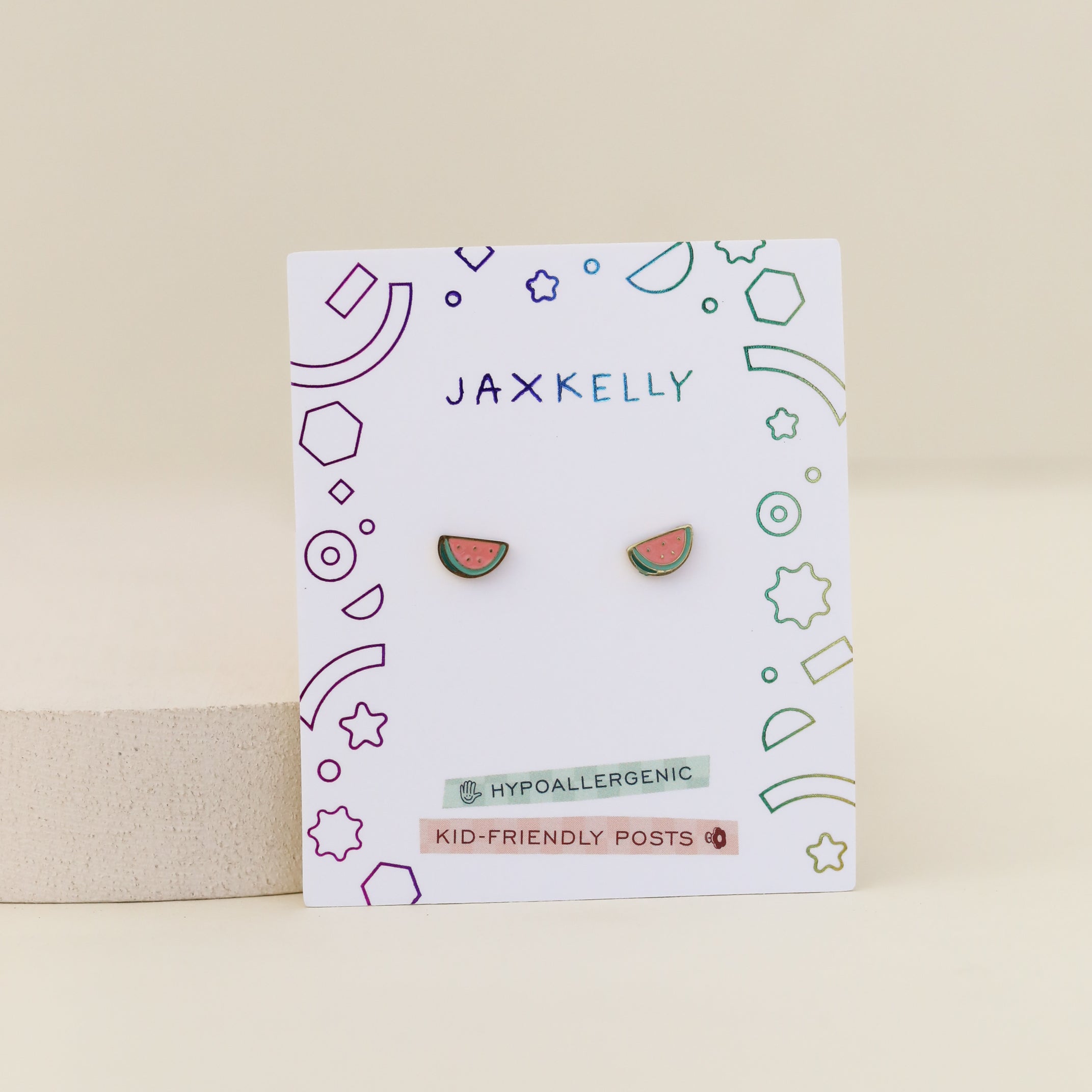 Watermelon Enamel Flat Back Kids Earrings are shown on a white JaxKelly card with colorful geometric designs, labeled “Hypoallergenic” and “Kid-Friendly Posts.”.