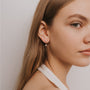 A young woman with long light brown hair wears a white halter top and the Dual Triangle Drop, a small, delicate CZ earring with sterling silver posts, while looking slightly away from the camera against a plain light background.