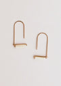The Mother of Pearl Gemstone Drop - Calming earrings feature minimalist gold-plated wire, U-shaped hooks, and horizontal white Mother of Pearl cylinder accents, displayed on a simple light background.