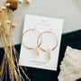 JaxKelly’s Citrine Hoop - Success earrings are displayed on a white card among dried flowers and clear quartz. These stunning citrine hoops are hypoallergenic, making them perfect jewelry for sensitive ears.
