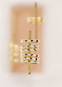 A close-up of several White Opal Inset Baguette rings, 18k gold plated and featuring square lab-grown opals, stacked on a vertical metal rod with a blurred background.