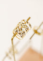 A close-up of several 18k gold plated rings stacked on a golden display stand, including the White Opal Inset Baguette ring with a shiny, reflective surface, all arranged neatly with a soft, blurred background.