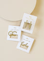 Three pairs of Large Ball Hoop earrings, gold plated with sterling silver posts, are displayed on white cards with JaxKelly wear good vibes in gold lettering, arranged against a light beige background.