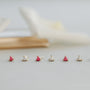 Six Tiny White Opal Heart gold-plated stud earrings are arranged in a row on a pale surface, each featuring lab-grown white opals set in delicate gold prongs against a softly blurred background.