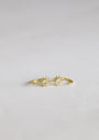 The Sun Huggie is a delicate gold ring with two small sun-shaped designs, each set with a central clear gemstone, beautifully displayed on a light, neutral background.