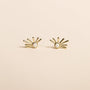 A pair of Sun Ray - White Opal stud earrings with 18k gold plating, featuring a central round lab-grown white opal and five gold bars radiating outward, shown against a plain beige background.