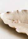 The Rose Quartz Mineral Point - Love rests on a gold-colored, leaf-shaped tray against a neutral background.