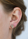 Close-up of a person’s ear wearing the Rose Gold Druzy Prong earring, featuring a star shape with sparkling gemstones and elegant 18k gold plating. The person's brown hair is pulled back against a softly blurred background.