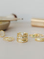 The Celestial Ring, a gold stacking ring with a central marquise-shaped stone and small diamonds, is shown among other gold rings on a light surface with blurred objects in the background.
