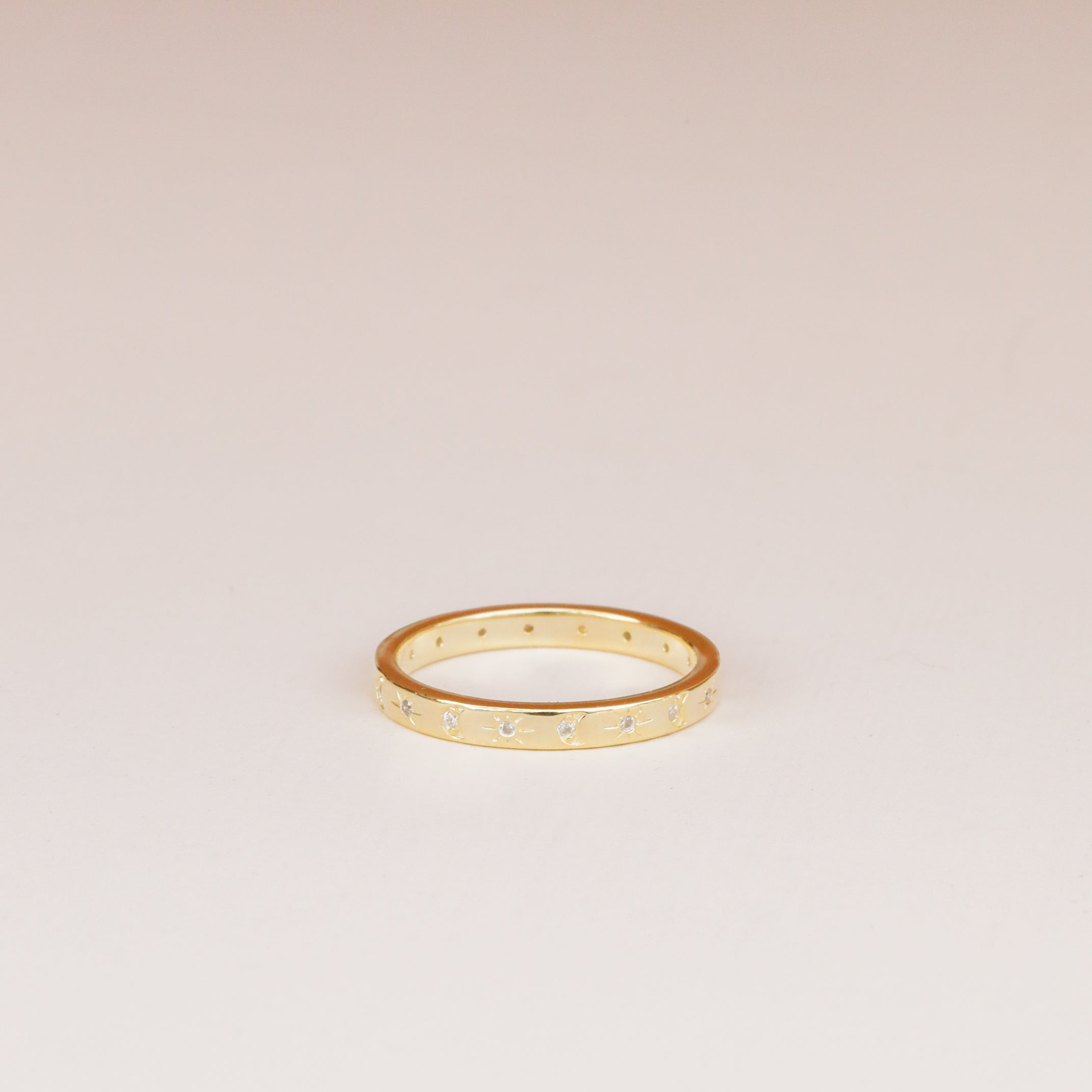 The Celestial Ring, a simple gold stacking ring with small star-shaped engravings, is displayed on a plain, light-colored background.