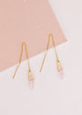 The JaxKelly Gemstone Threader - Rose Quartz earrings feature gold plating, delicate chains, and rose quartz pendants, displayed on a soft pink and white background.
