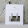 The Pavé Silver Hoop earrings, sparkling with rhodium plating, are showcased on a white card with gold "JaxKelly" and "wear good vibes" text, set against textured gray stones.