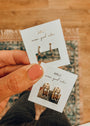 A hand with pink nail polish holds two cards showing pairs of Jay Kelly Bold Hoop 18k gold plated earrings. The cards, set against a patterned rug, feature the message: “wear good vibes.”.