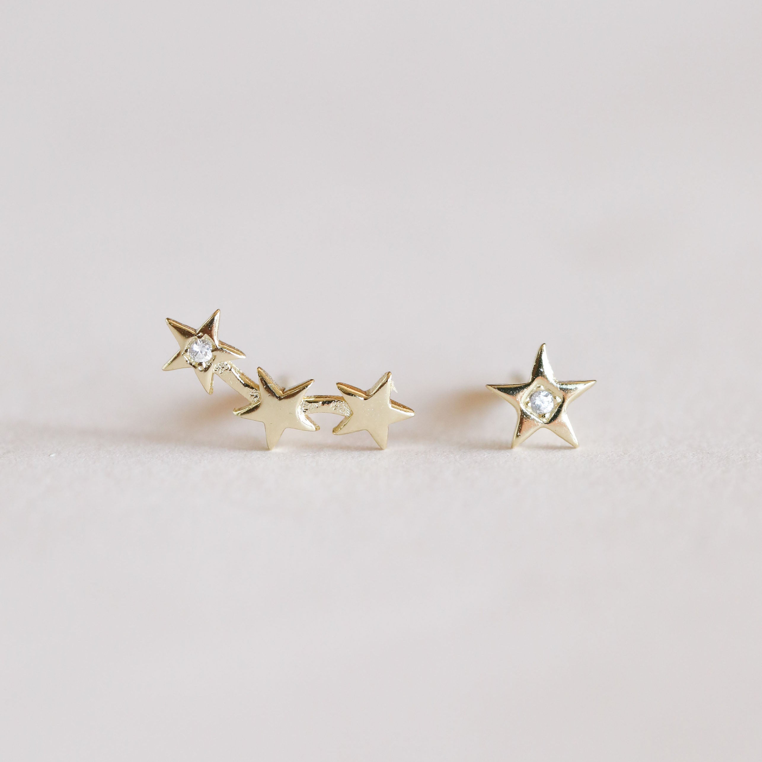 The Star & Constellation earrings: one features three gold-plated stars with sparkling stones, the other a single star with a clear stone—celestial-inspired jewelry for star lovers.