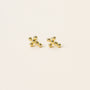 A pair of Cross Stud earrings, small 18k gold plated studs with sterling silver posts shaped like jacks game pieces, shown on a plain light background.